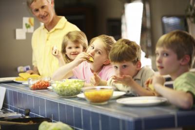A group of children making and eating hard-shell tacos.