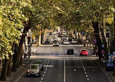 Photo of multiple cars driving along a tree lined road.