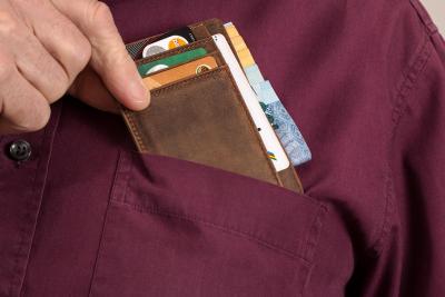 A close up photo of a man's front pocket with a bill fold holding credit cards to represent shopping addiction.