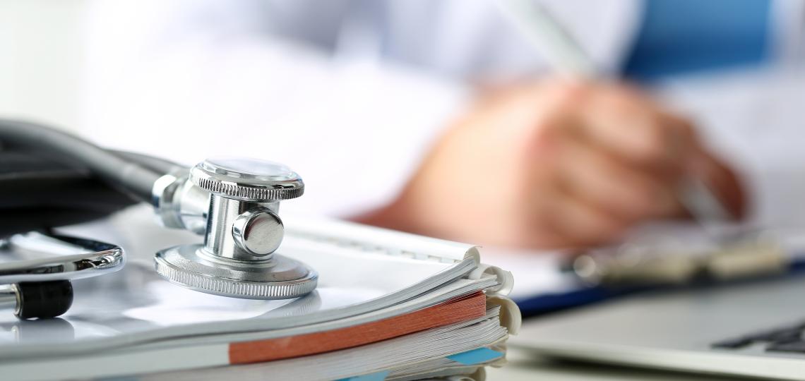 Close up of notebooks and a blurry hand of a doctor writing notes