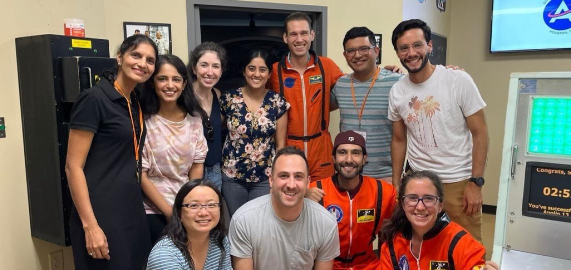 group of people smiling with 3 dressed like astronauts