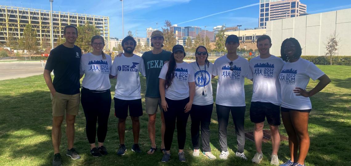 Members of the student committee lined up in the grass on a bright day.