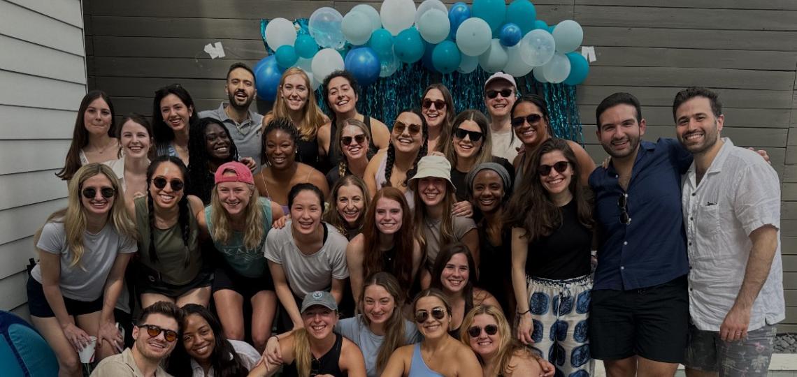group of people smiling in front of balloons