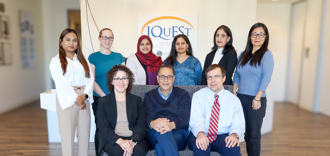 three people sitting on a couch and six people standing behind the couch