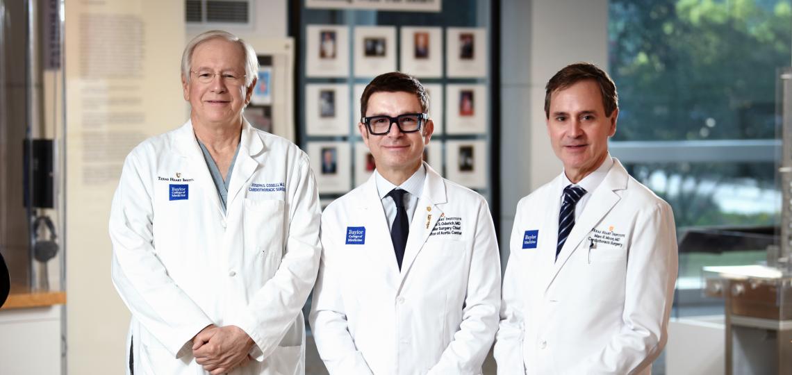 Three male doctors in white lab coats posing in a medical facility.