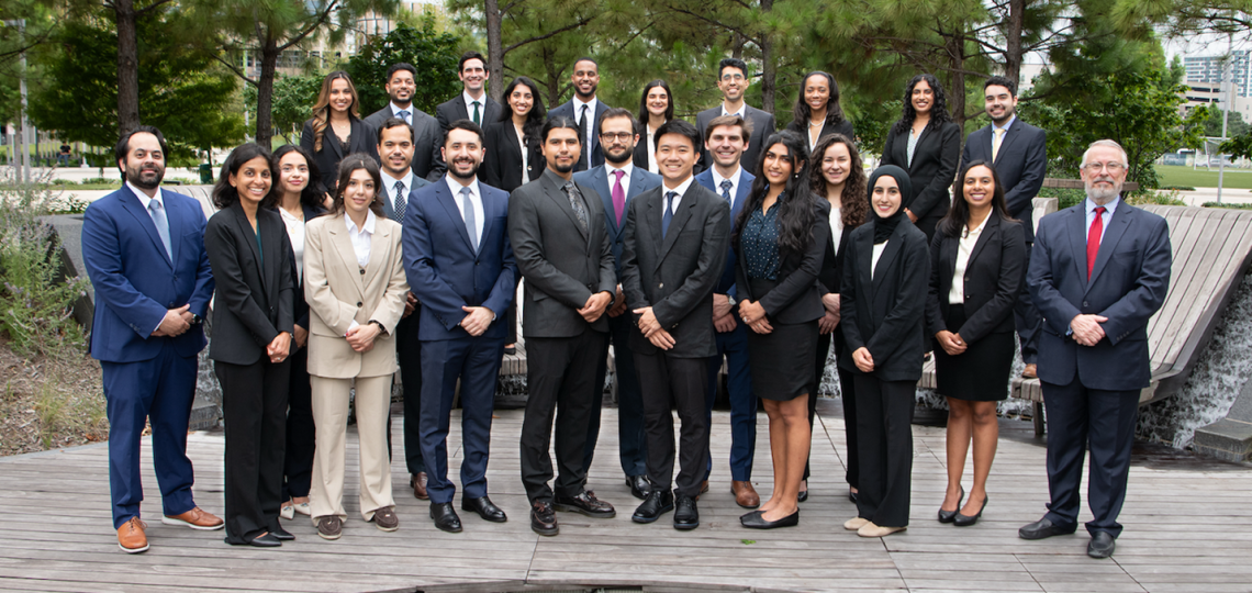 A large group in formal dress standing in rows outside.