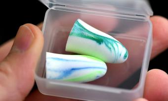 Close up photo of blue and white earplugs in a plastic box container. 