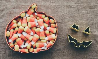 Photo of candy corn in a bowl shaped like an pumpkin. 