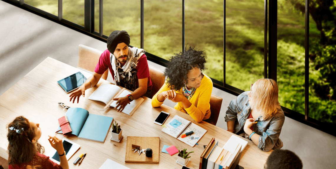 A group of students gathered around at a study table with books open
