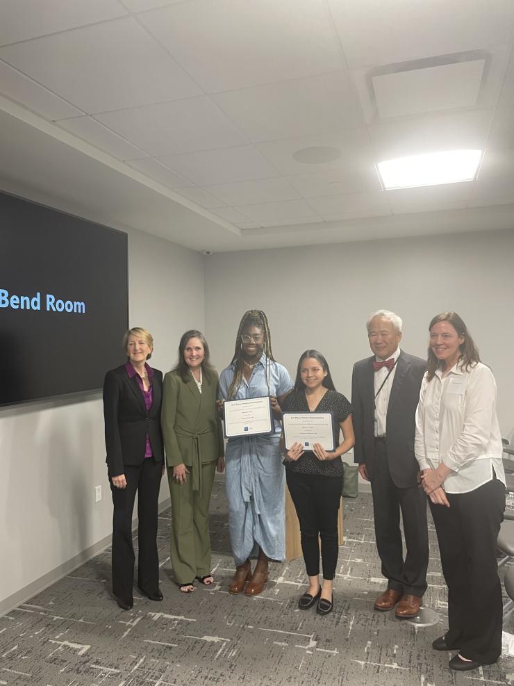 award winners holding certificates and smiling with a group of people
