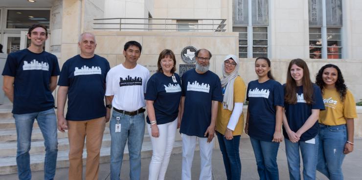 A group of 9 people standing in front of a building