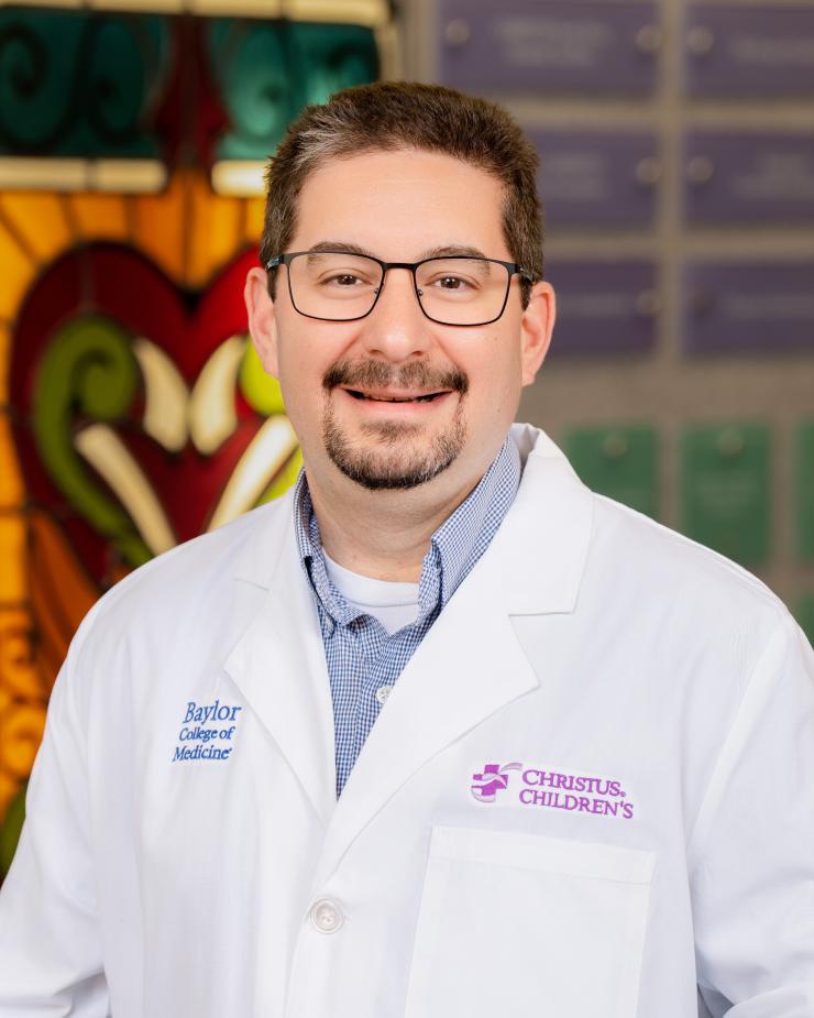 man with brown hair and thin, black glasses on smiling