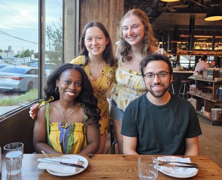 Four people smiling at a restaurant.