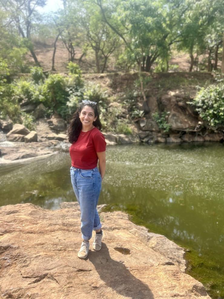 woman standing on a rock in water, smiling
