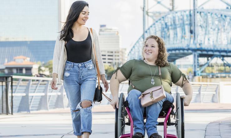 Two women enjoying a bright day on a boardwalk.