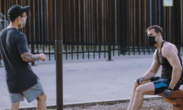 Two people exercising outdoors while wearing face masks.