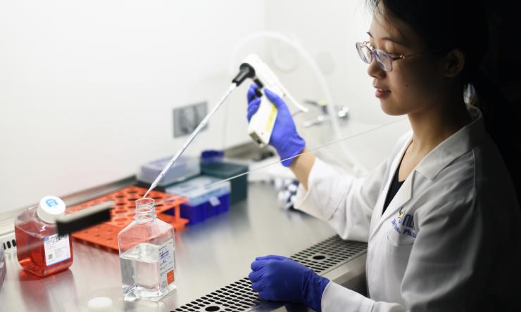 A chemist in a laboratory holding a long pipette while conducting an experiment.