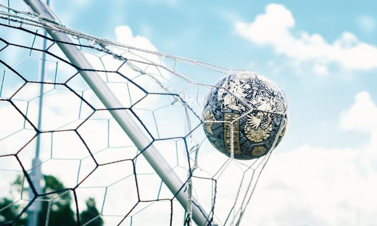 Photo of a soccer ball hitting the goal net.
