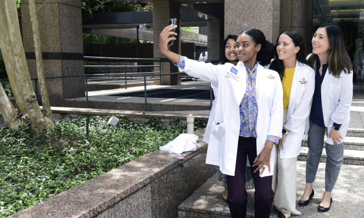 Four students taking an outdoor group selfie