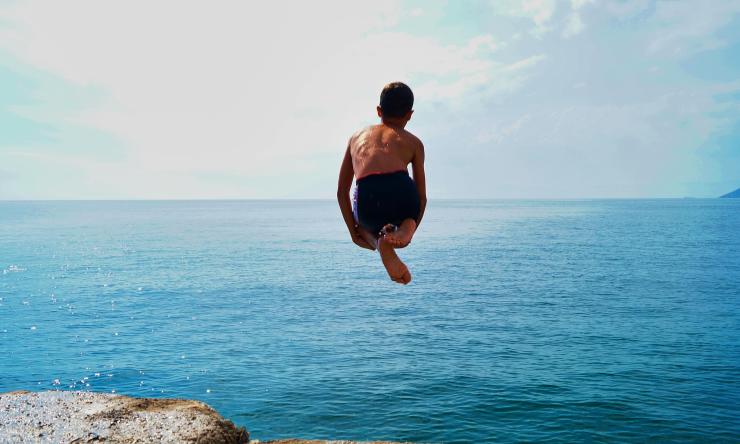 Child jumping off into ocean
