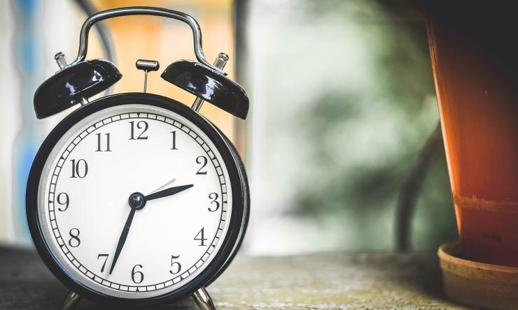 Photo of a round, black clock with alarm bells on top. 
