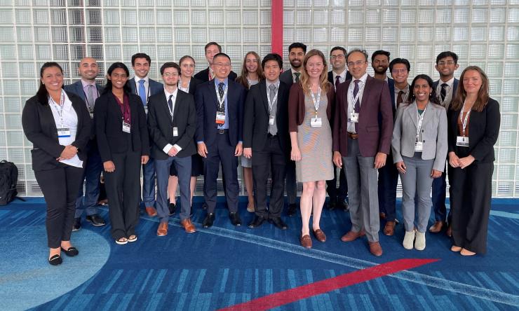 group of people standing in front of a white wall.