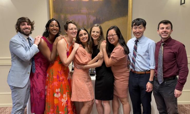 A group of smiling students posing in front of a painting